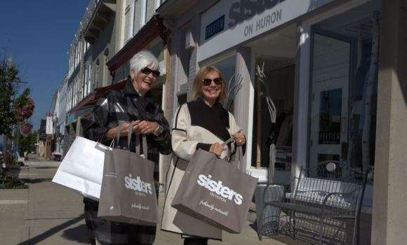 two women smiling and walking in Southampton holding shopping bags