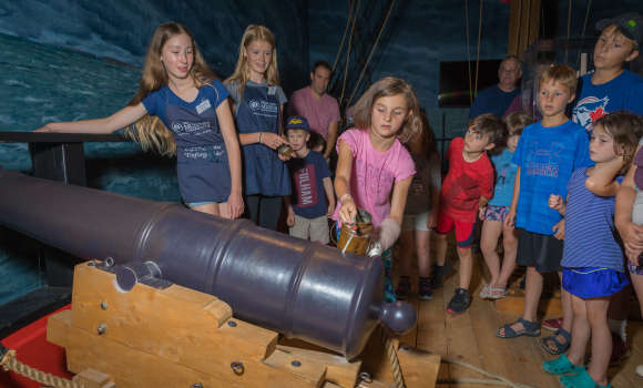 Group of kids gathered around an old canon at the museum