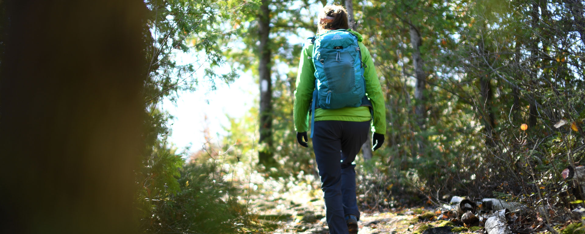 woman with a backpack on a hiking trail walking away from the camera
