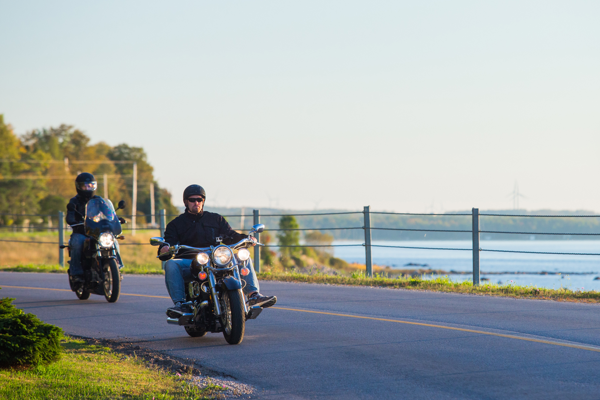 Two motorcyclers on Lakeshore motorcycle tour beside shoreline