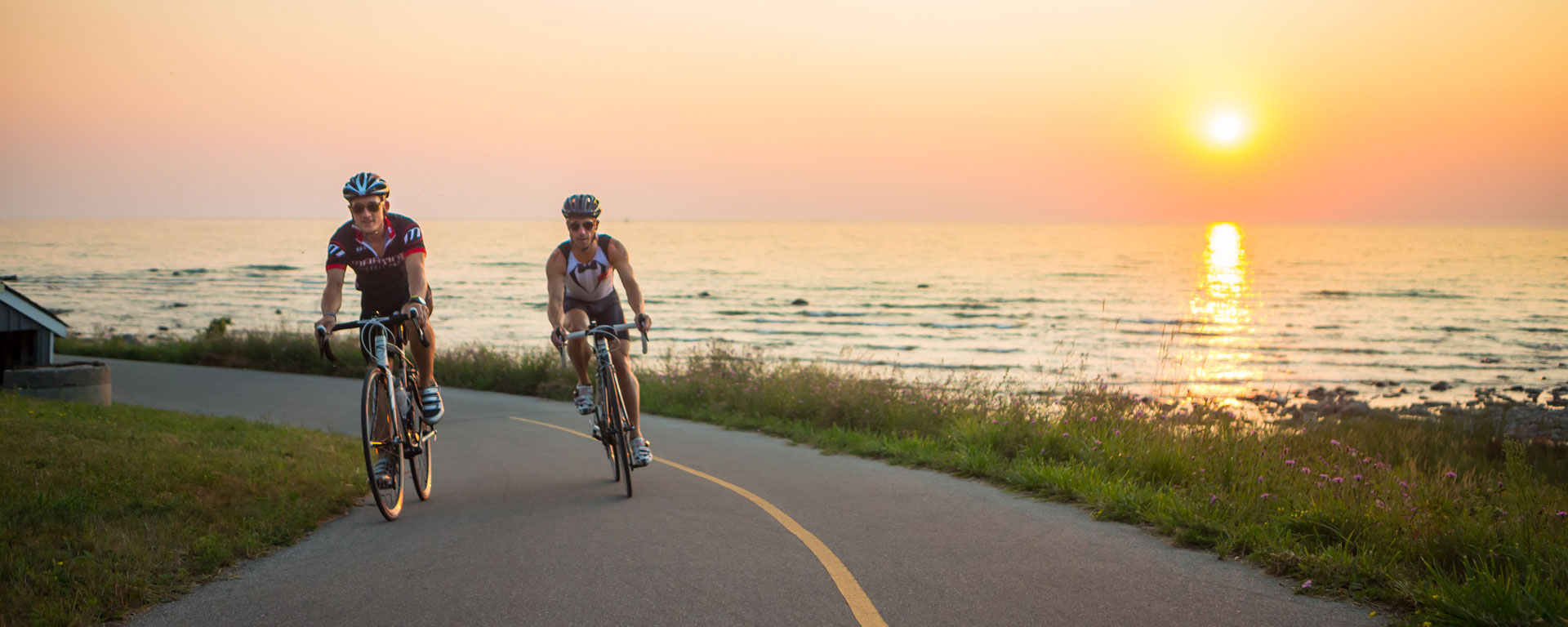 two cyclists on the empty road with a golden sunset in the background