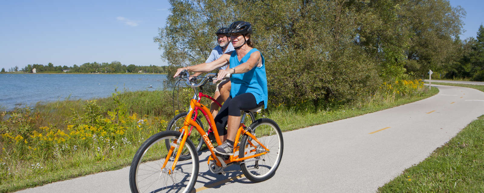 Happy couple on a cycling tour using a red and orange bike