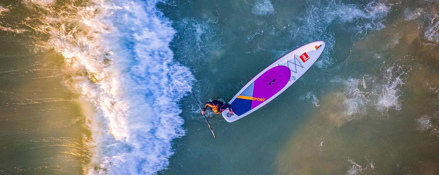 Overhead drone look straigh down on a Paddle Boarder close to shore