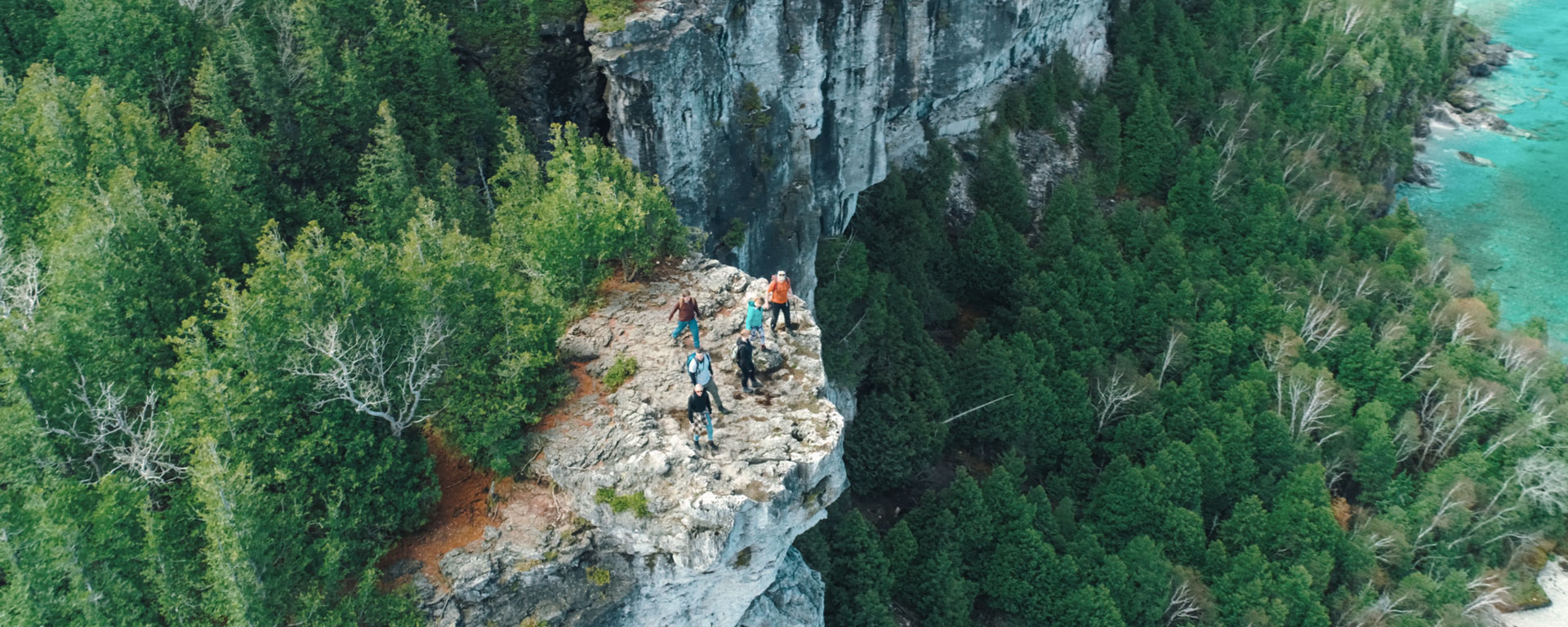 drone shot of people hiking on the top of a cliff