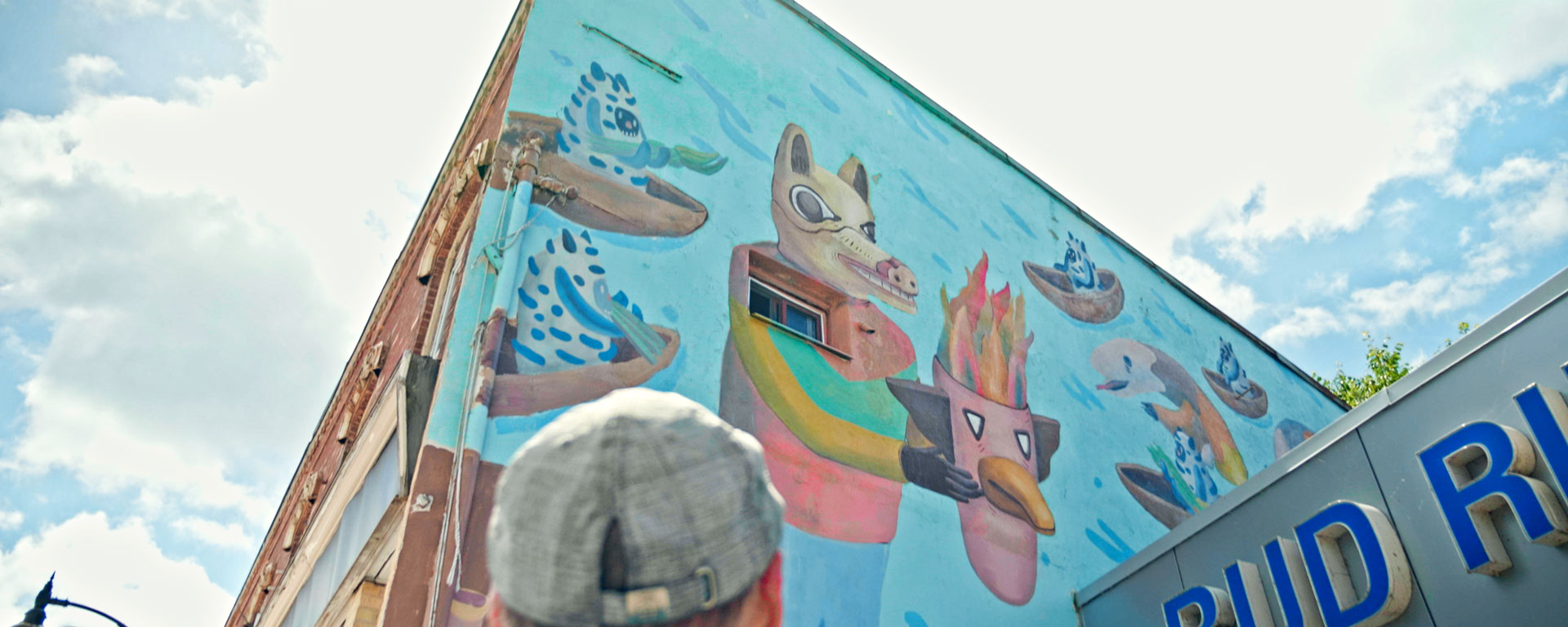 the camera is pointed up towards a large wall mural of an animal type character in Paisley