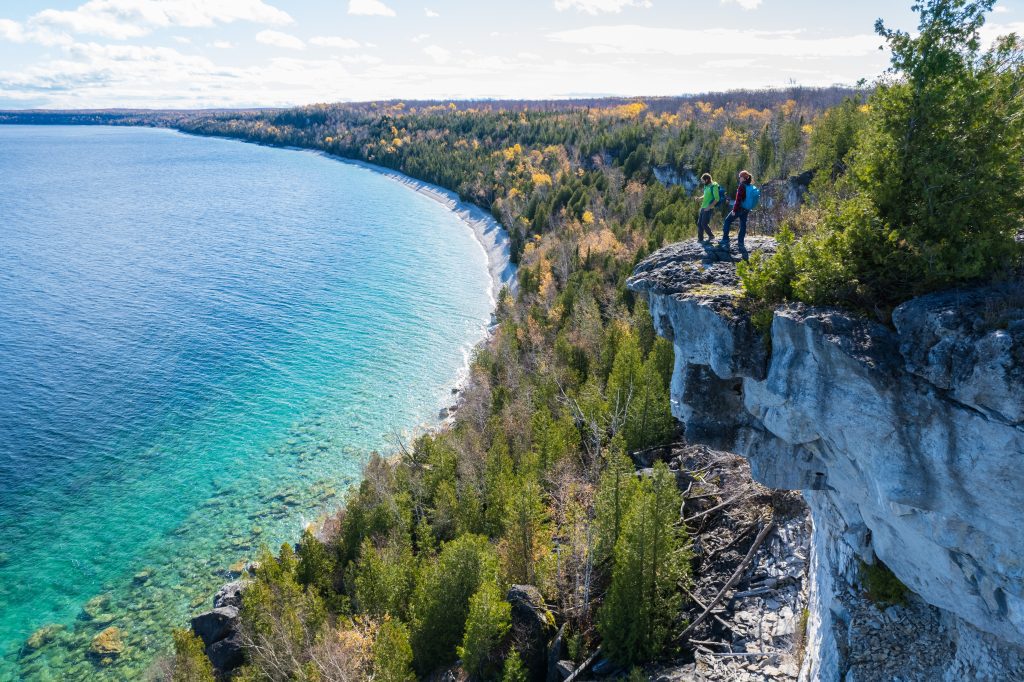 Two people standing on a cliff's edge on the Bruce Peninsula