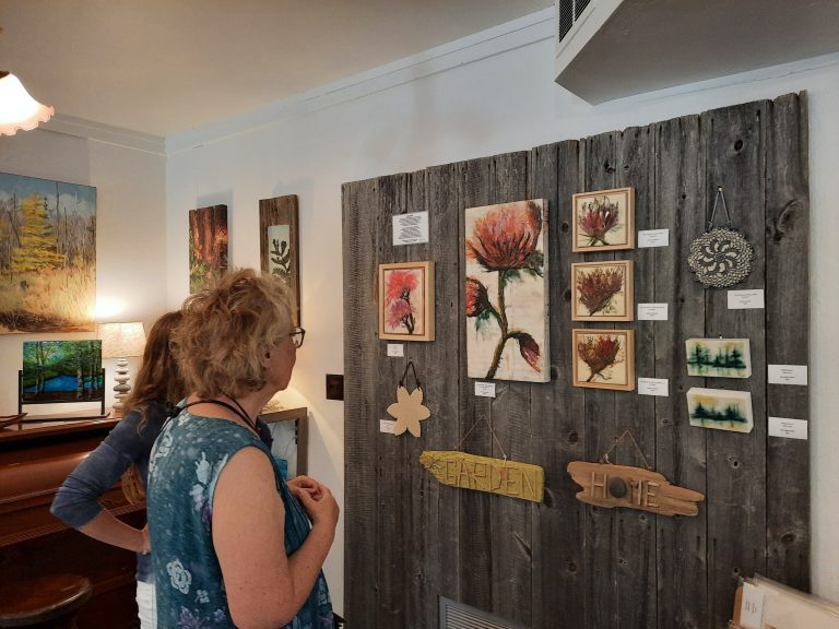 Two women looking at artwork on the wall.