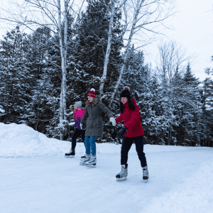 Three people ice skating outdoors