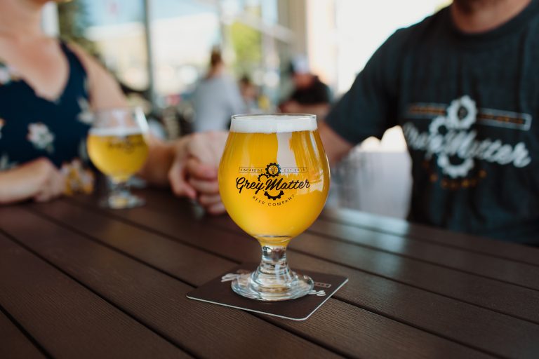 Two pints of beer on an outdoor patio table.
