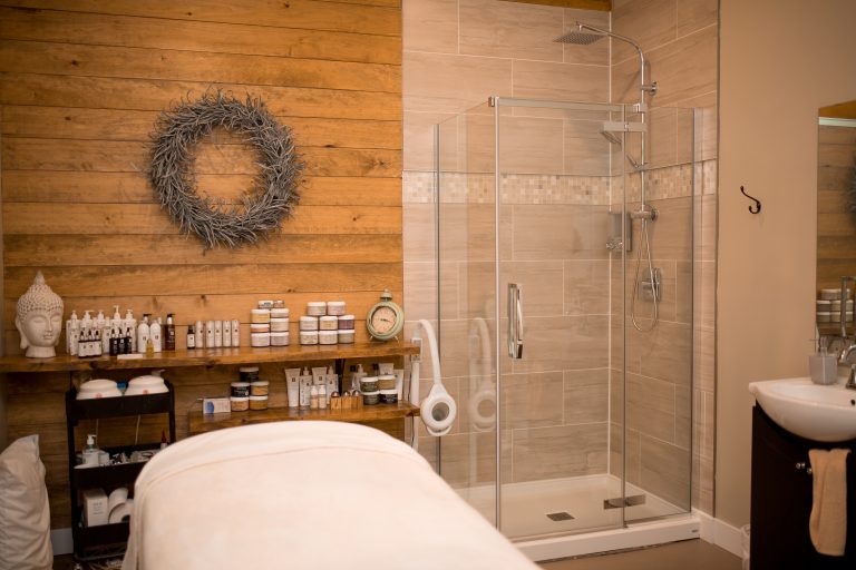 A spa treatment room with a bed, shower, and decor.