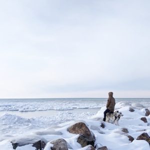 Person with two dogs overlooking icy frozen Lake Huron