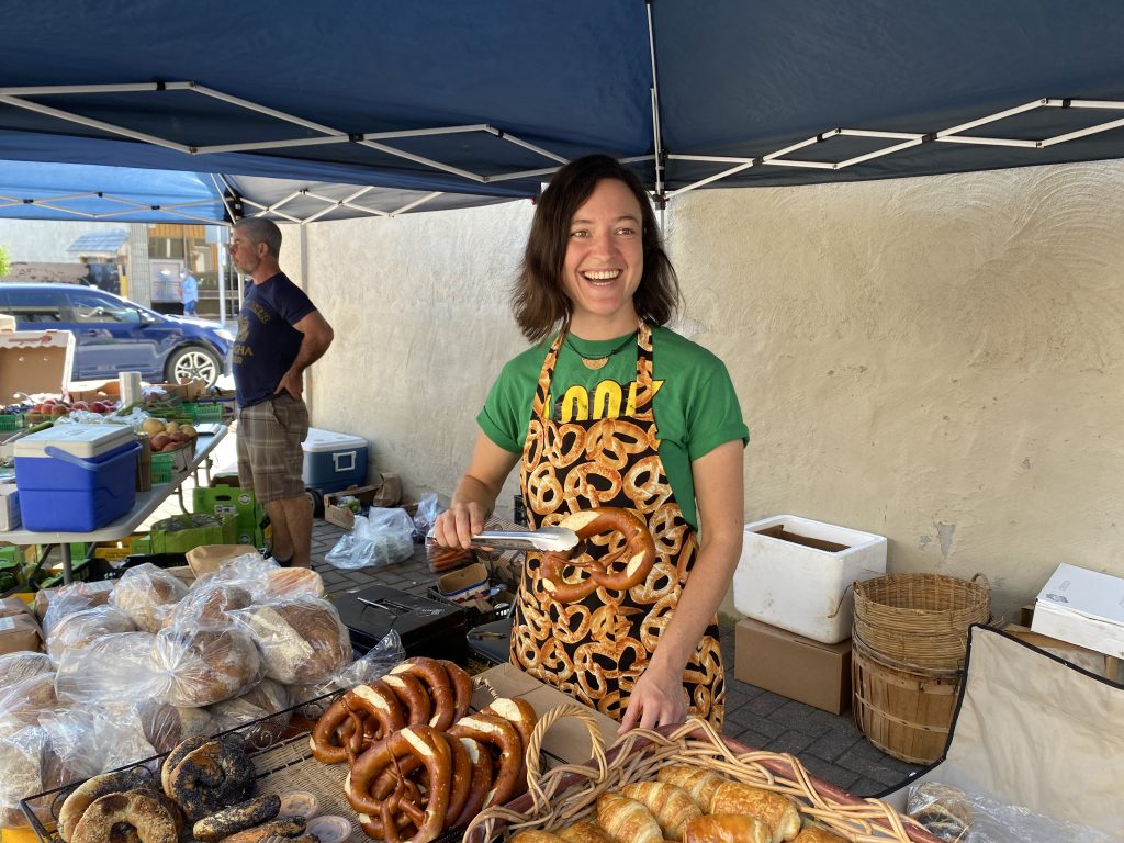 Person handing out pretzels at farmers' market