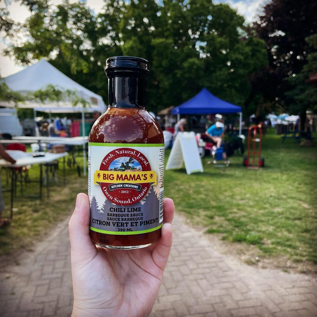 Hand holding up jar of BBQ sauce at Kincardine Market in the Park