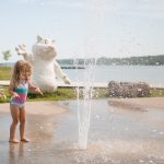 Young girl playing at outdoor slash pad with Wiarton Willie statue in the background